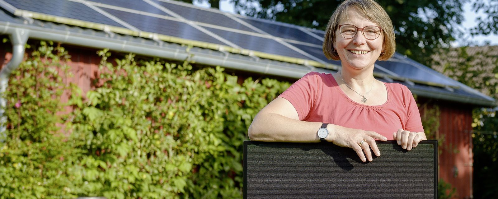 Eine zufriedene Solaranlagen-Besitzering hält ein PV-Modul